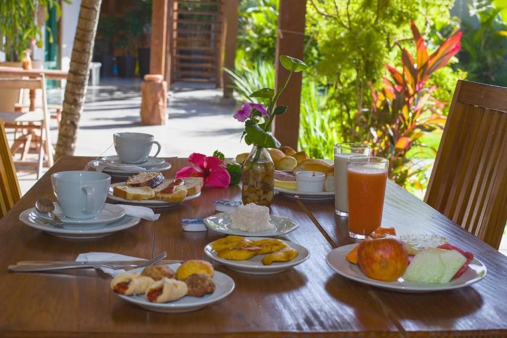 Mesa de café da manhã com frutas, suco, pães e hibisco