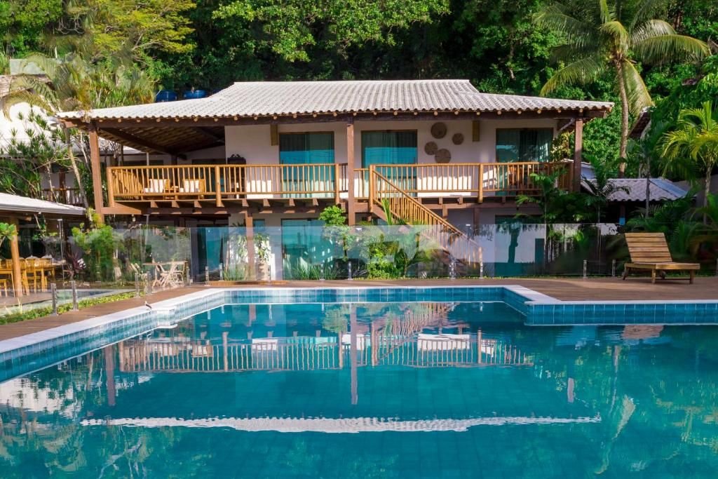 Piscina com a casa principal de dois pavimentos ao fundo
