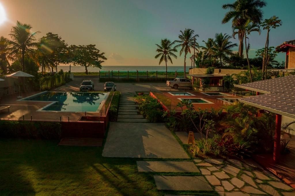 Fim de tarde no jardim com piscina, coqueiros e o mar ao fundo